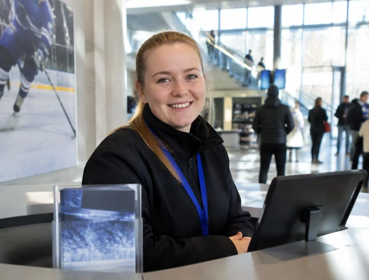 Arena staff member smiling at an information desk in a bright arena lobby